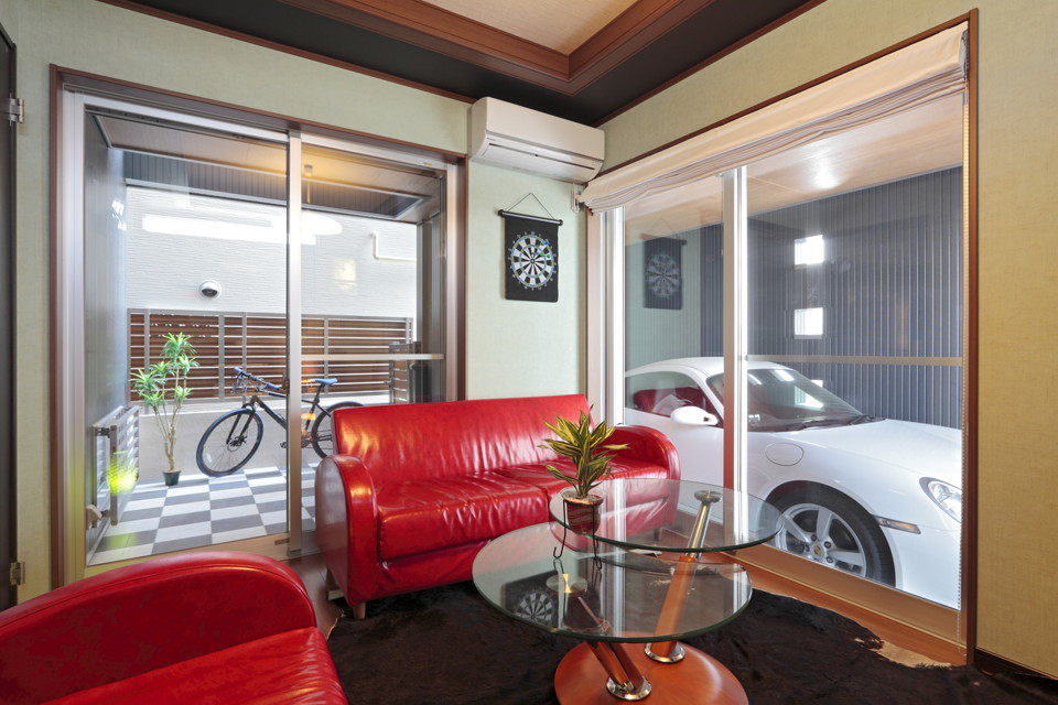 「愛車」を眺めて過ごせるお部屋はテラスへとつながる設計になっています。真っ赤なソファが空間に彩りを添えて、素敵な空間に仕上がっています。